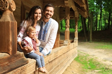 Photo of Happy family in Ukrainian national clothes on wooden terrace