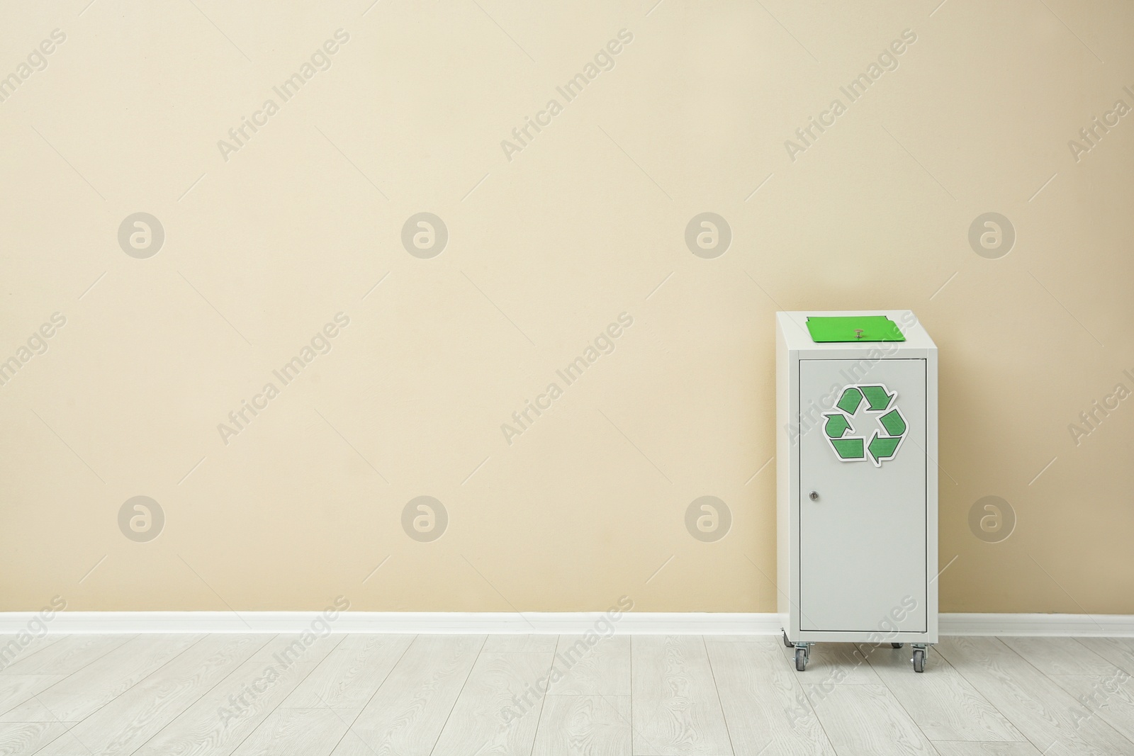 Photo of Trash bin with recycling symbol near color wall indoors. Space for text