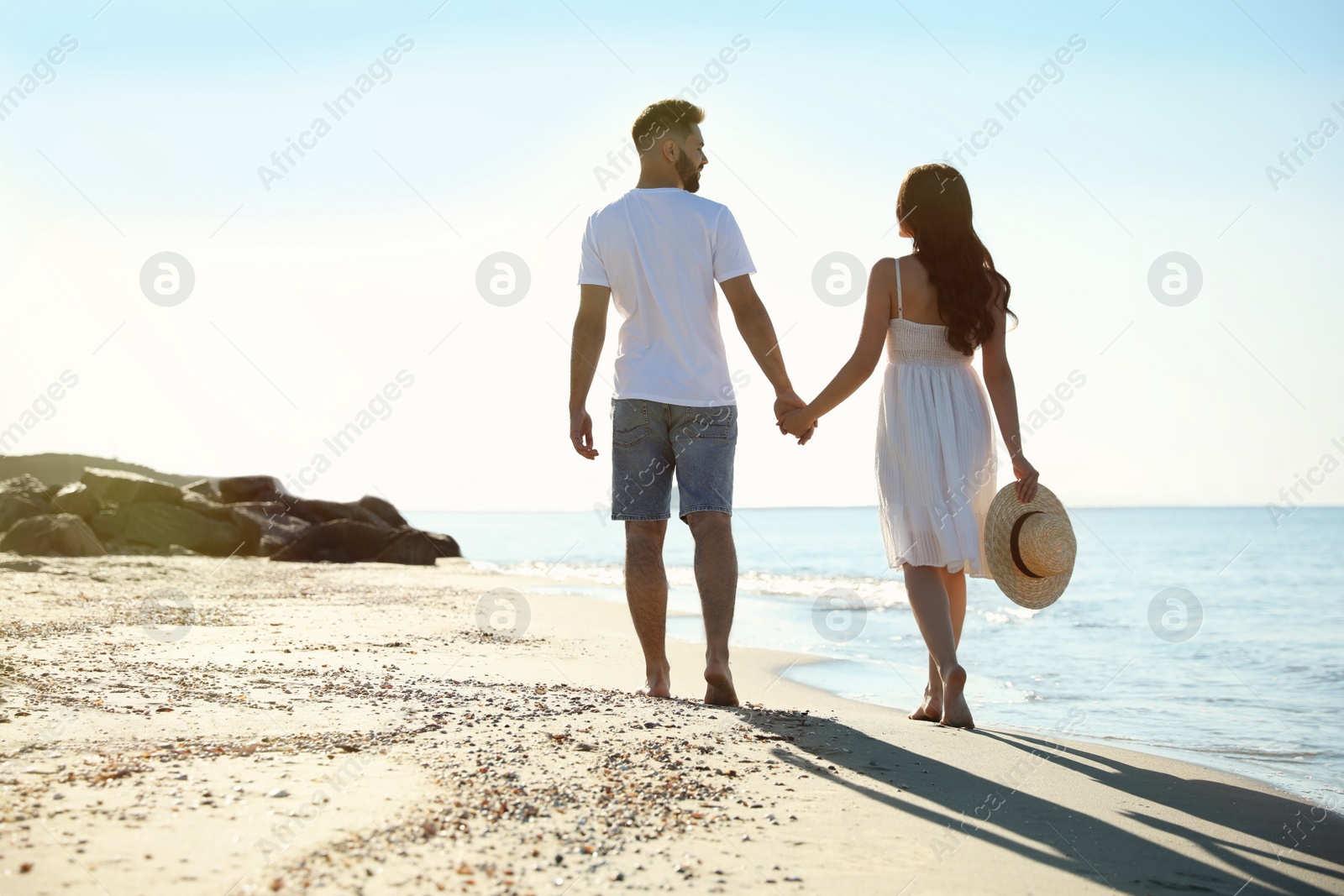 Photo of Happy young couple walking on beach near sea. Honeymoon trip