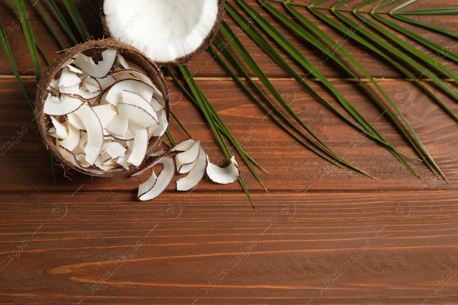 Photo of Tasty coconut chips on wooden table, above view