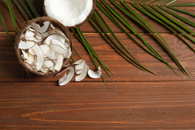 Photo of Tasty coconut chips on wooden table, above view