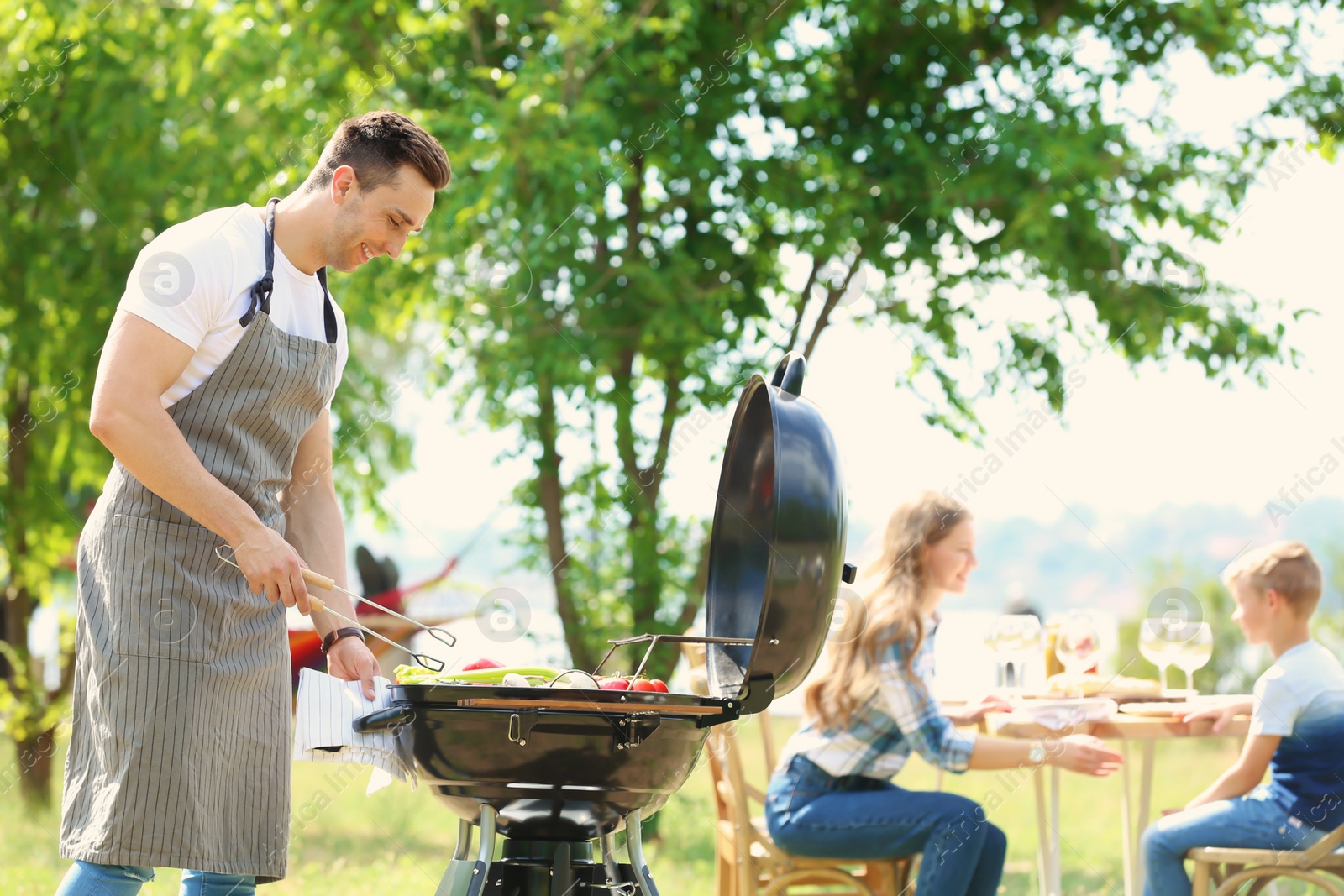 Photo of Happy family having barbecue with modern grill outdoors