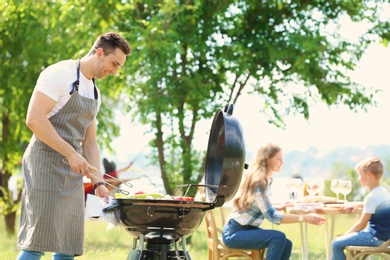 Happy family having barbecue with modern grill outdoors