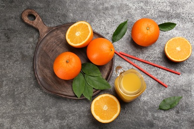 Photo of Delicious orange juice and fresh fruits on grey table, flat lay