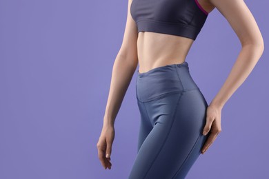 Photo of Woman wearing sportswear on violet background, closeup. Space for text