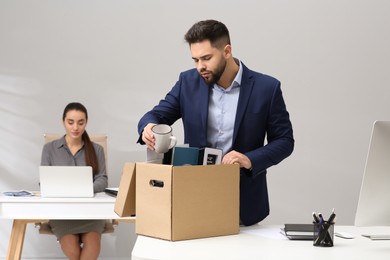 Photo of Dismissed man packing personal stuff into box in office