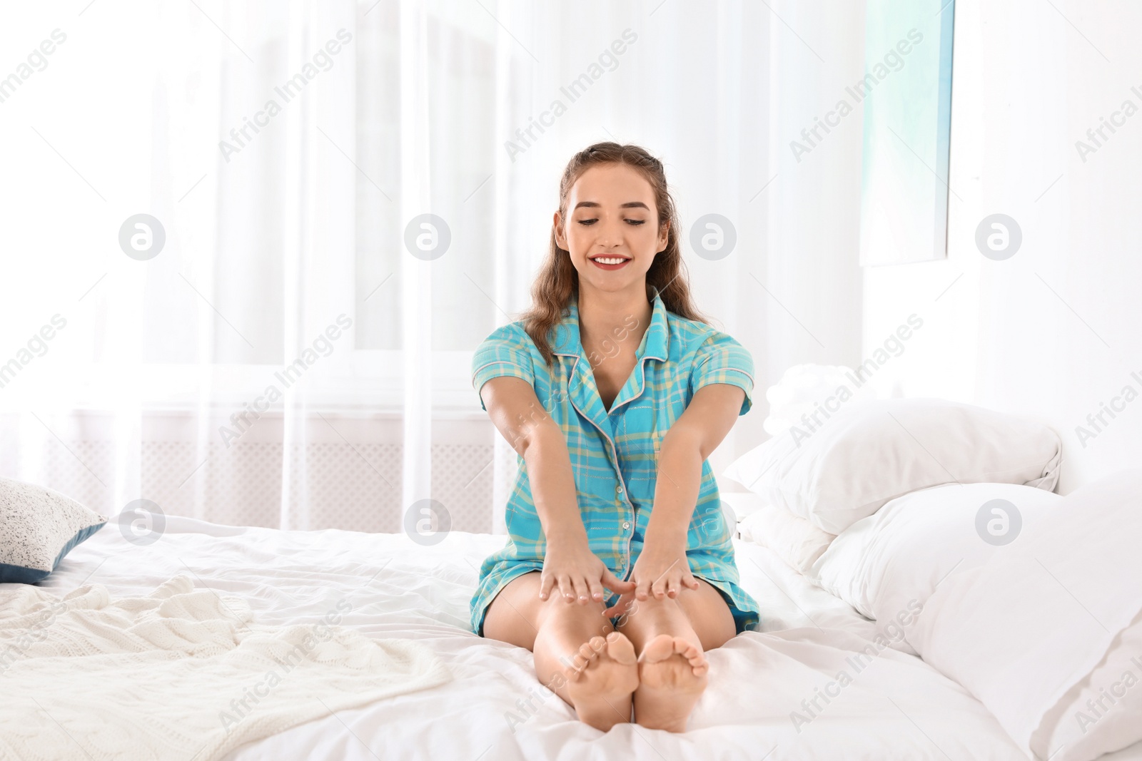 Photo of Young woman doing exercise on bed at home. Morning fitness