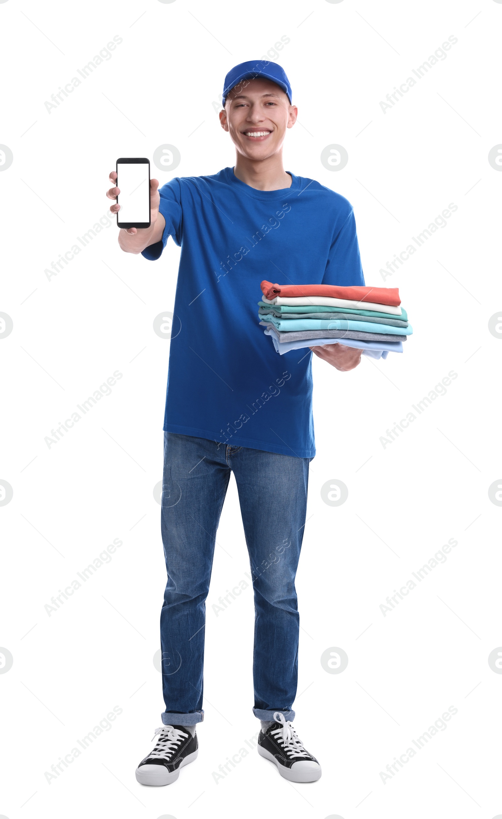 Photo of Dry-cleaning delivery. Happy courier holding folded clothes and smartphone on white background