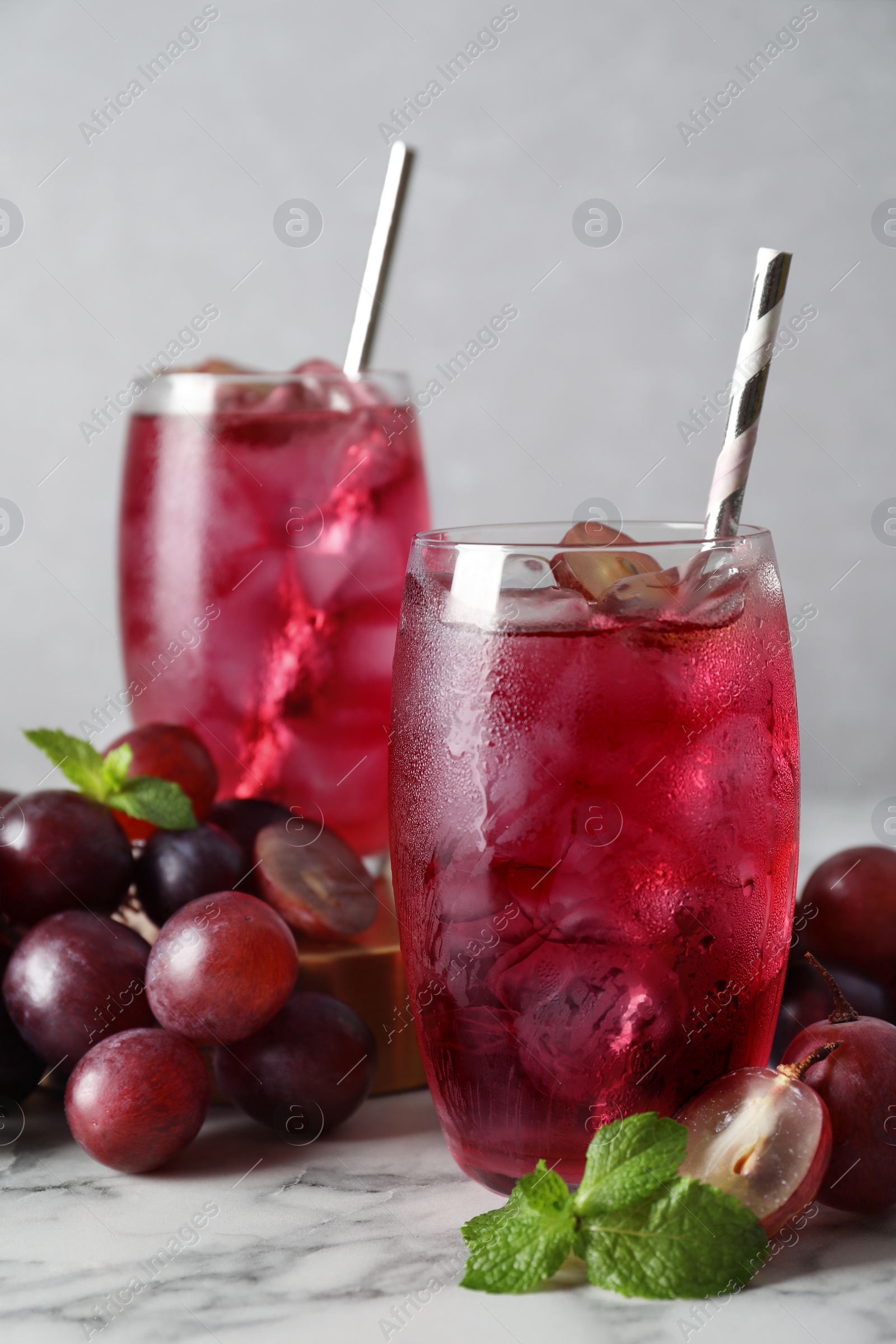 Photo of Delicious grape soda water with mint and berries on white marble table. Refreshing drink