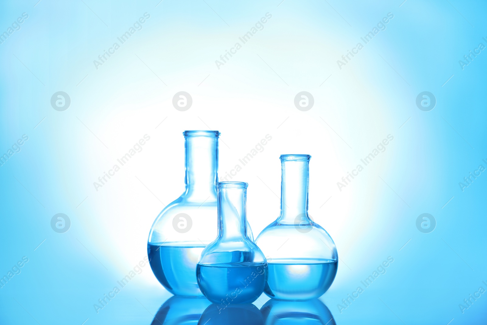 Photo of Laboratory glassware with liquid on color background. Solution chemistry