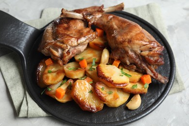 Tasty cooked rabbit meat with vegetables on table, closeup