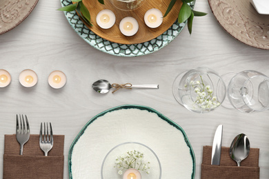 Elegant table setting with green plants on white wooden background, flat lay