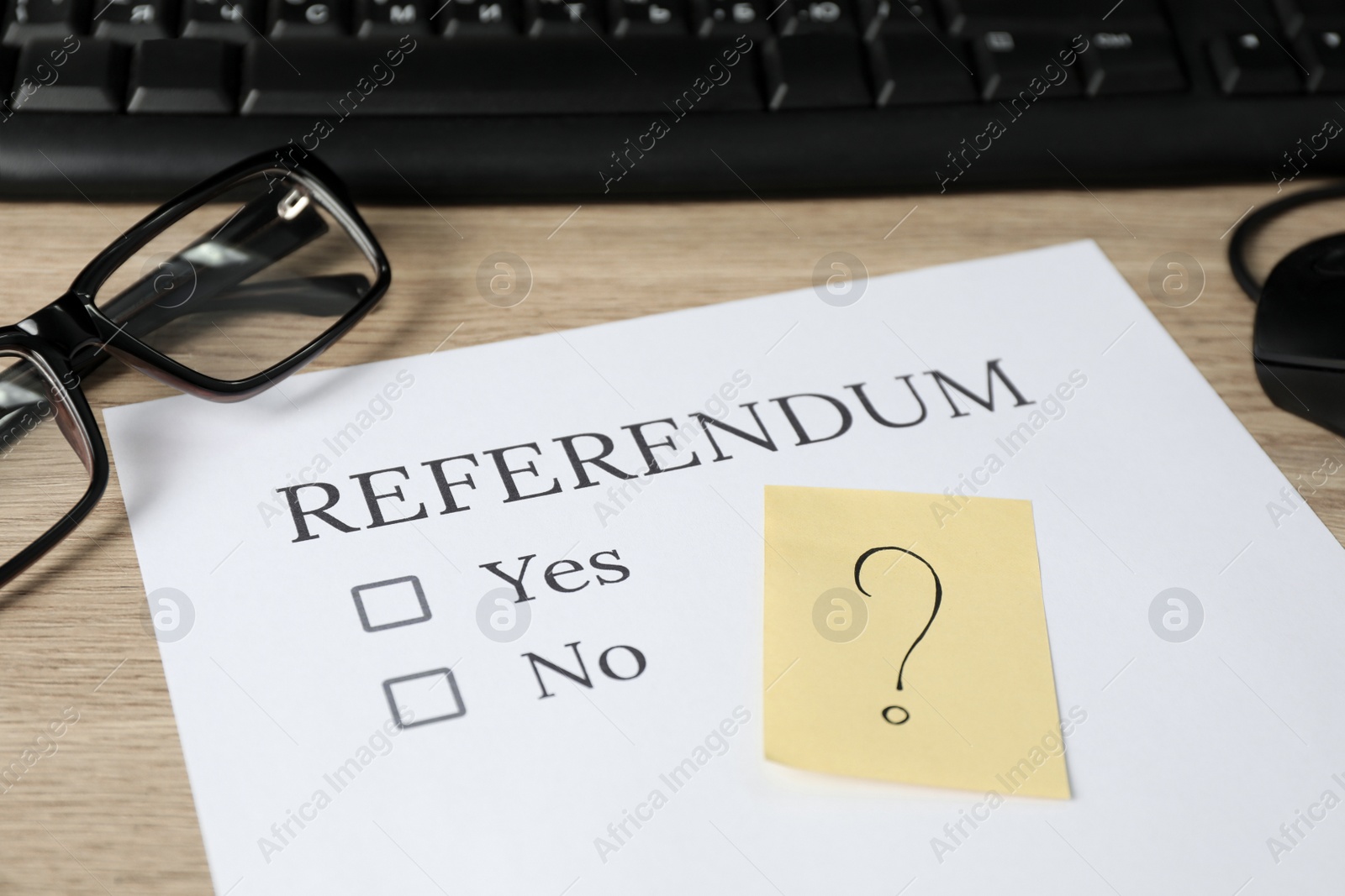 Photo of Referendum ballot, glasses and sticky note with question mark on wooden table, closeup