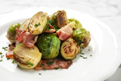 Photo of Delicious Brussels sprouts with bacon on plate, closeup