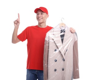 Dry-cleaning delivery. Happy courier holding coat in plastic bag and pointing at something on white background