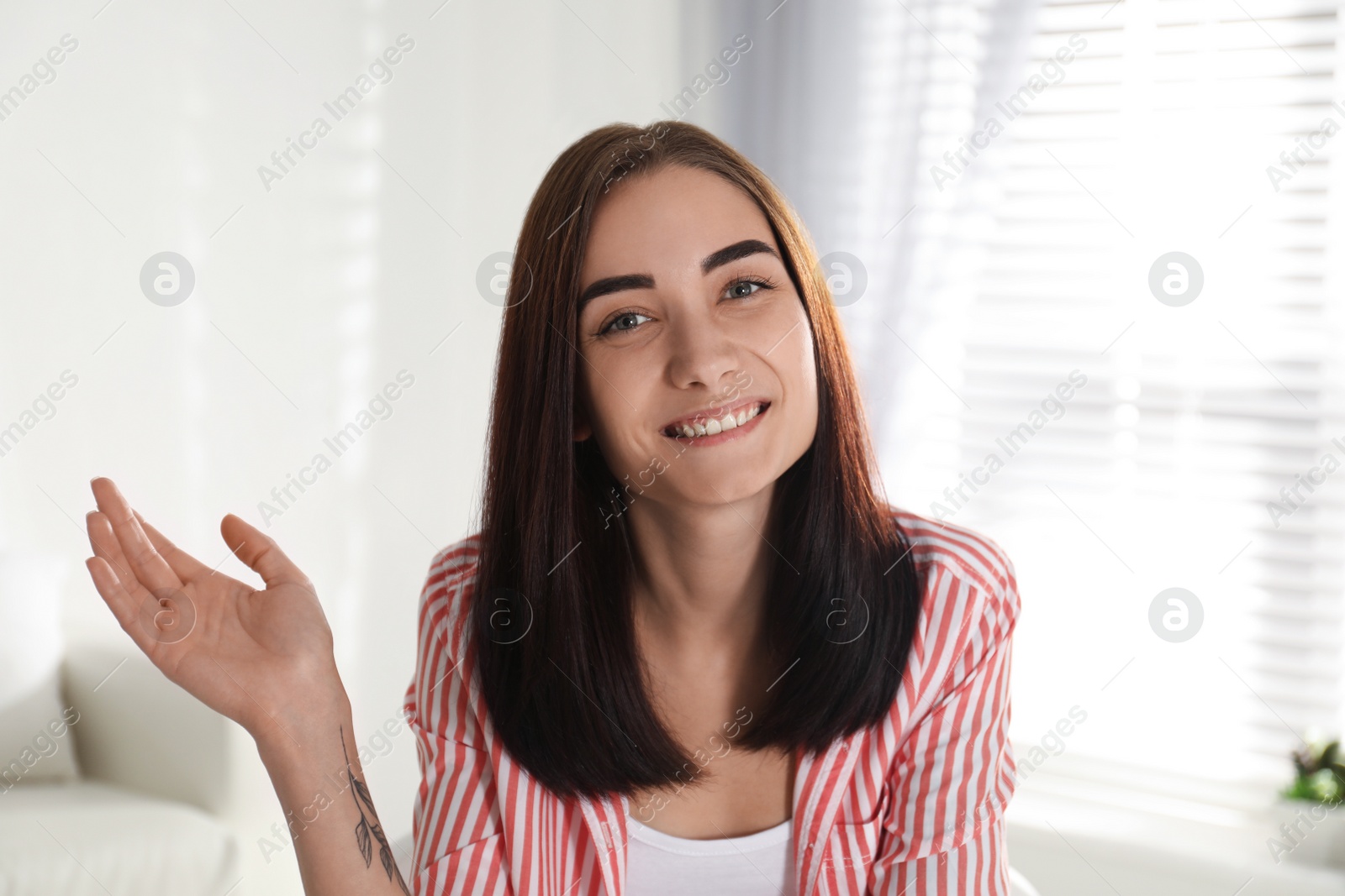 Photo of Young woman talking to her coworkers through video conference indoors, view from webcam