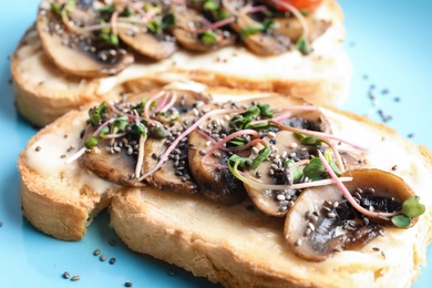 Tasty toasts with mushrooms, sprouts and chia seeds on color background, closeup