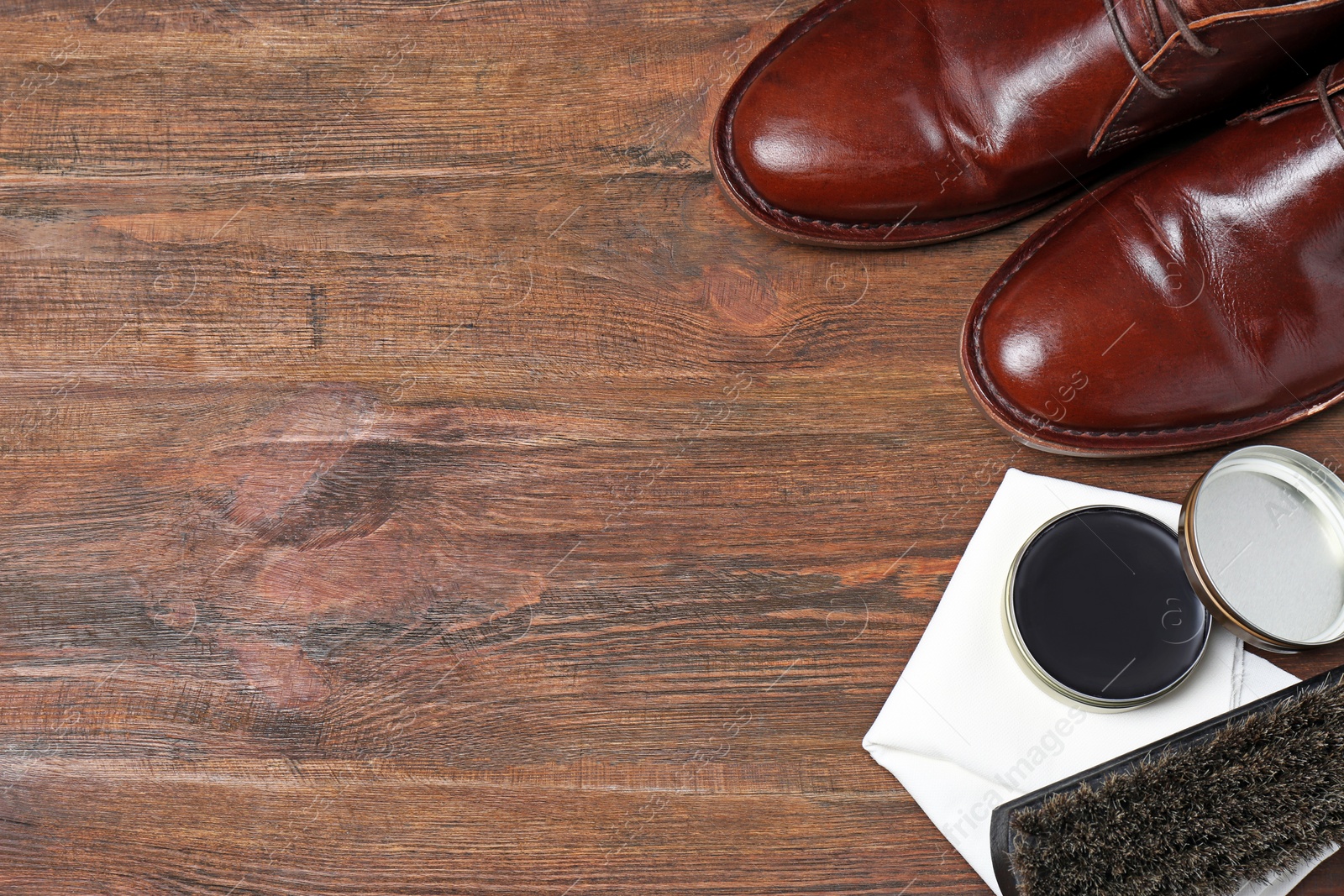 Photo of Flat lay composition with footwear and shoe shine kit on wooden background, space for text