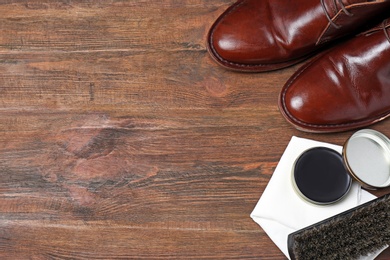 Flat lay composition with footwear and shoe shine kit on wooden background, space for text