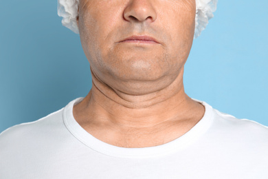 Photo of Mature man with double chin on blue background, closeup