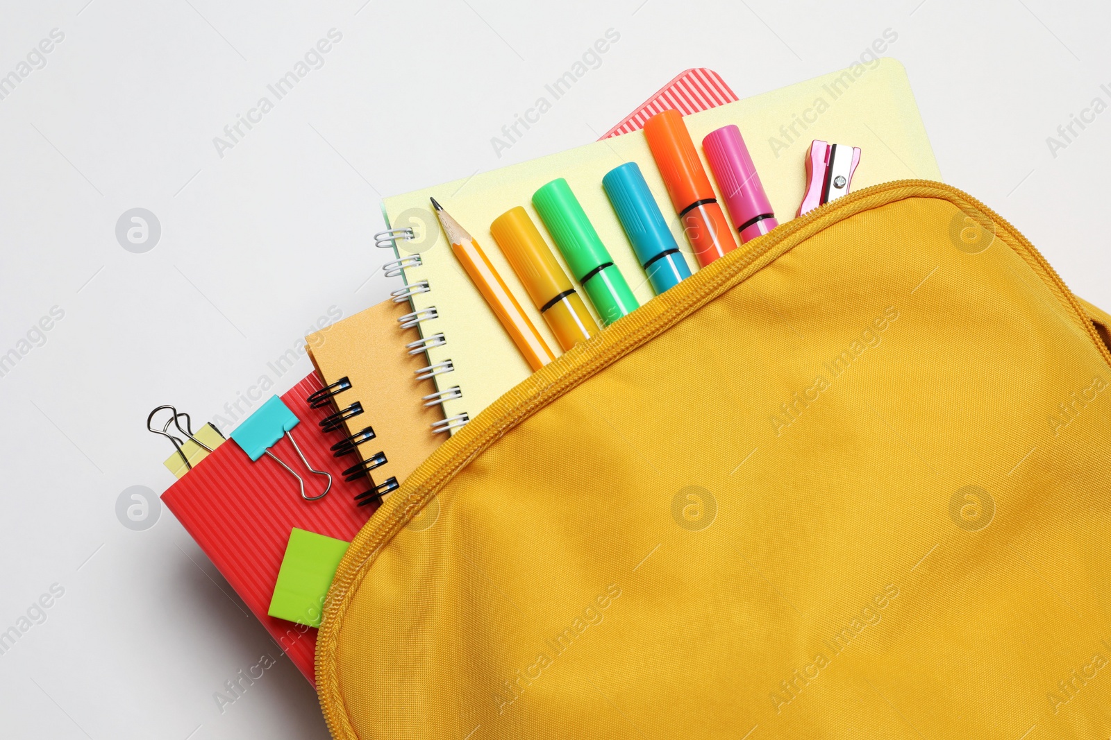 Photo of Backpack with different school stationery on white background, top view