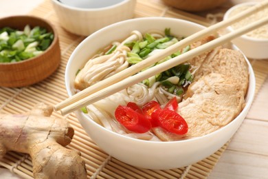 Photo of Delicious ramen with meat and ingredients on white wooden table, closeup. Noodle soup