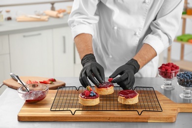 Male pastry chef preparing desserts at table in kitchen, closeup