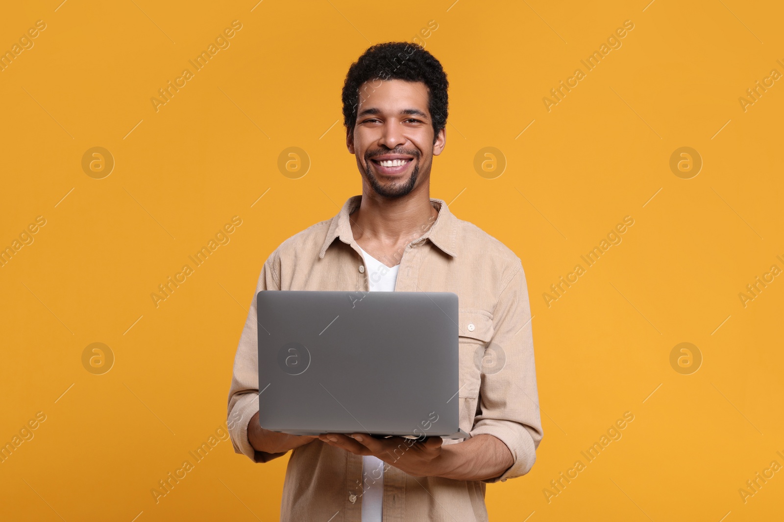 Photo of Happy man with laptop on orange background