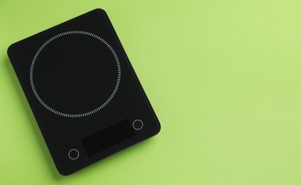 Photo of Modern digital kitchen scale on light green background, top view. Space for text