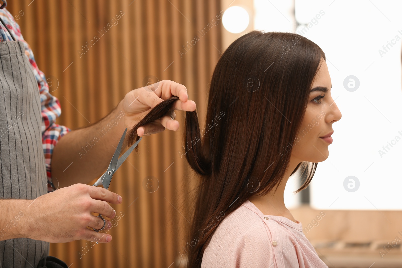 Photo of Barber making stylish haircut with professional scissors in beauty salon