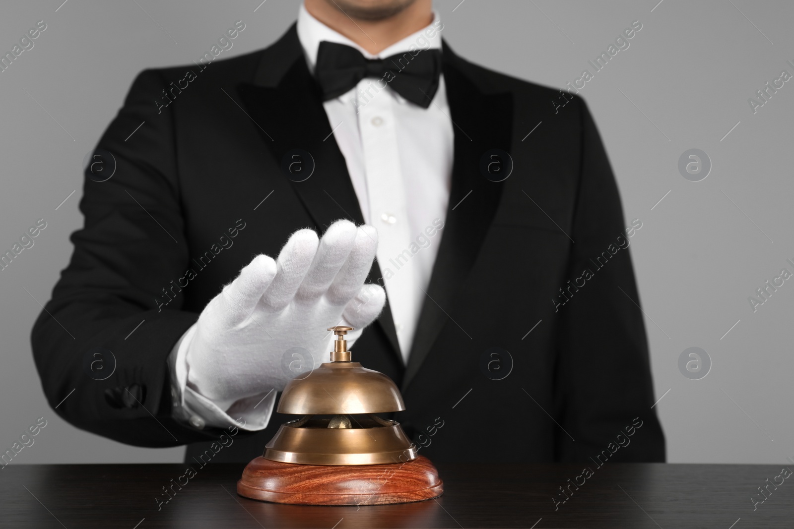 Photo of Butler ringing service bell at table, closeup