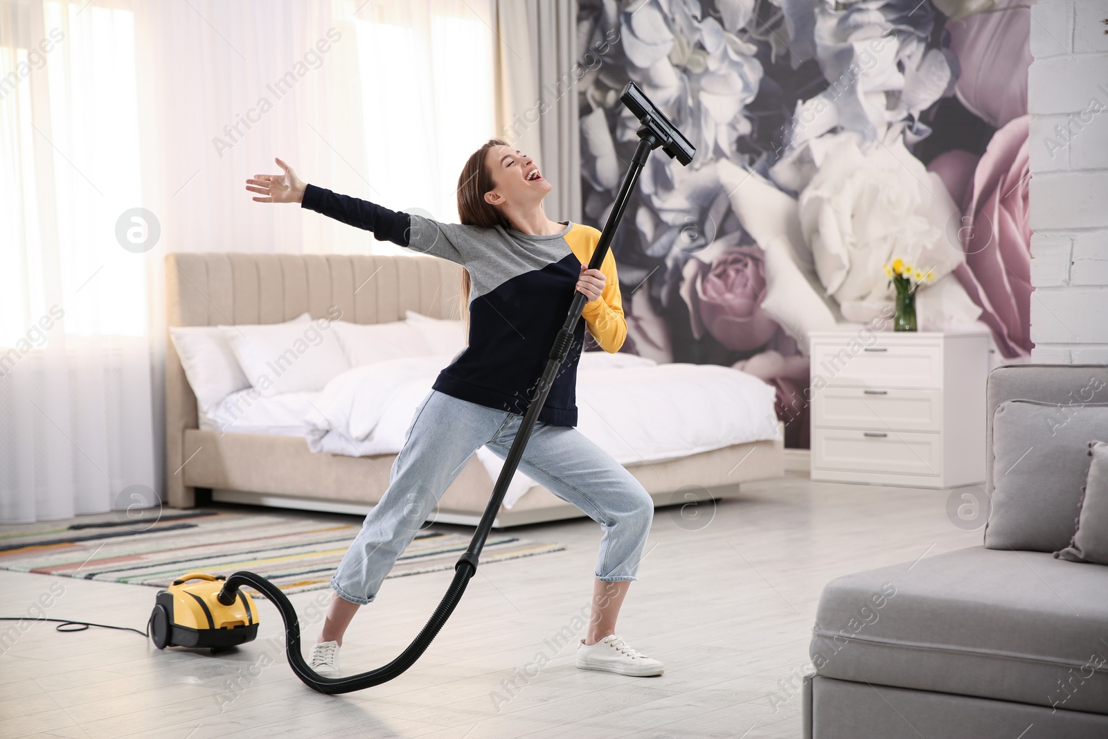 Photo of Young woman having fun while vacuuming at home