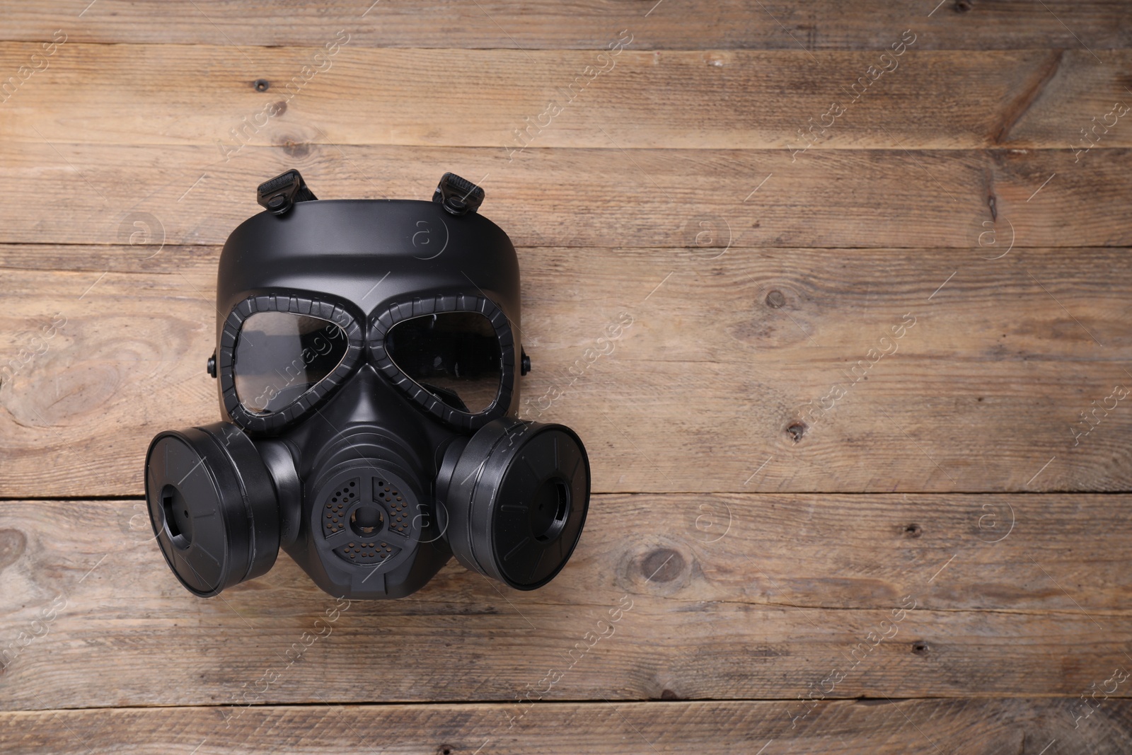 Photo of One gas mask on wooden background, top view. Space for text