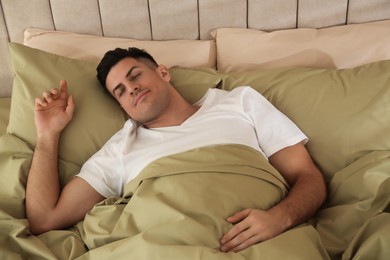 Man sleeping in bed with green linens at home