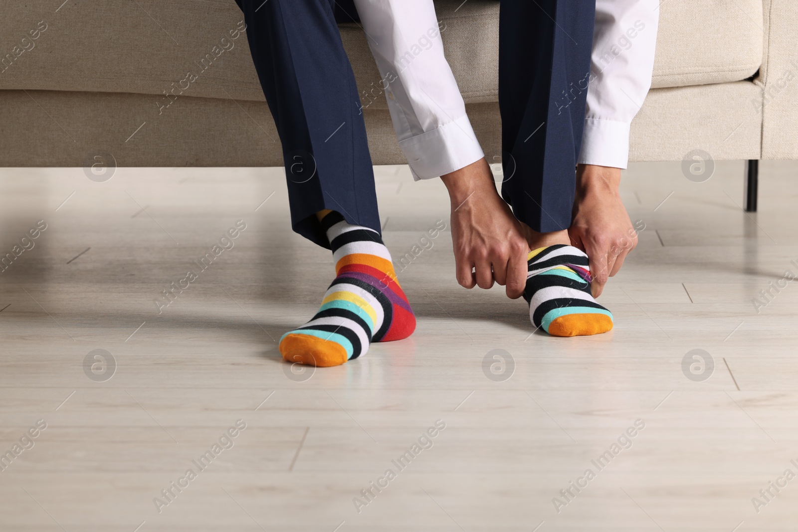 Photo of Man putting on colorful socks indoors, closeup