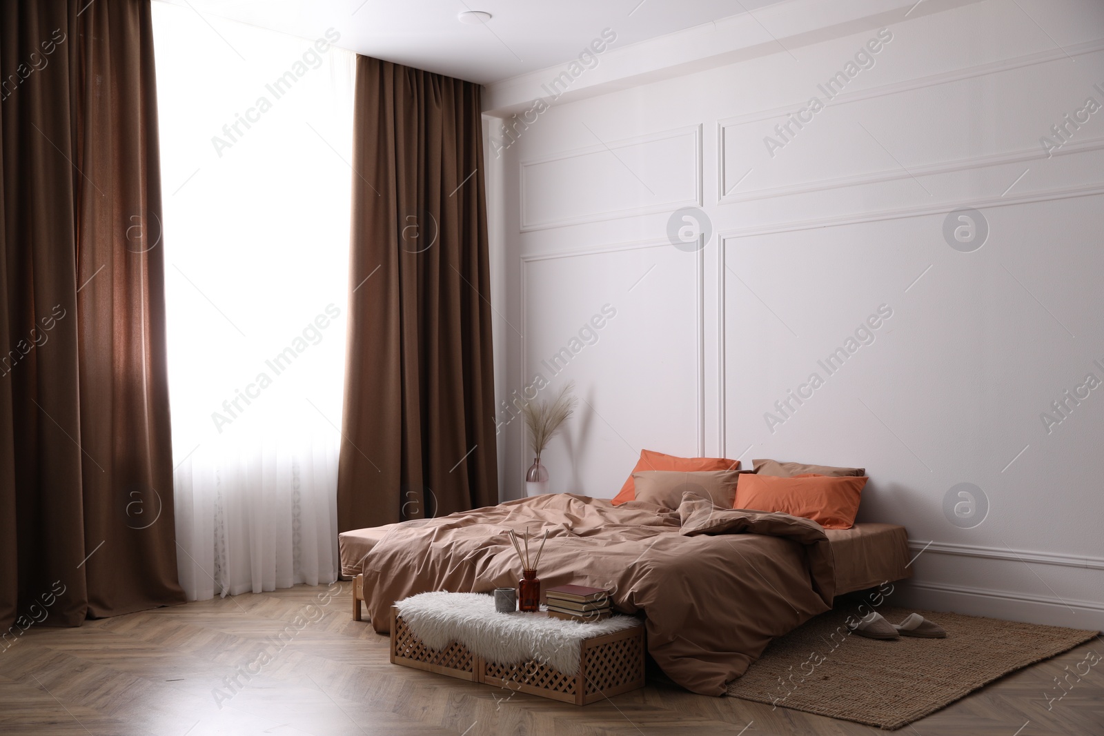 Photo of Bed with orange and brown linens in stylish room