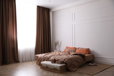 Bed with orange and brown linens in stylish room