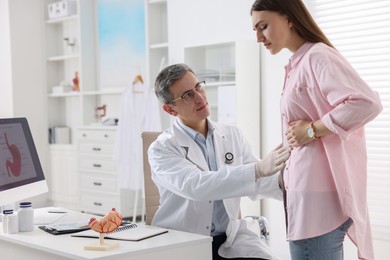 Photo of Gastroenterologist examining patient with stomach pain in clinic