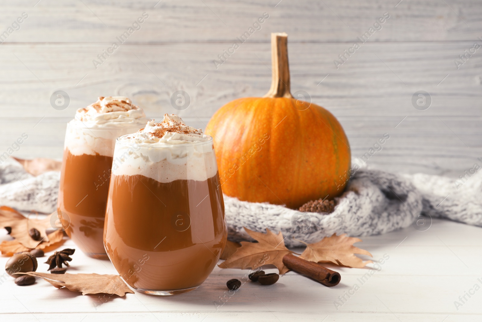 Photo of Glasses with tasty pumpkin spice latte on wooden table. Space for text