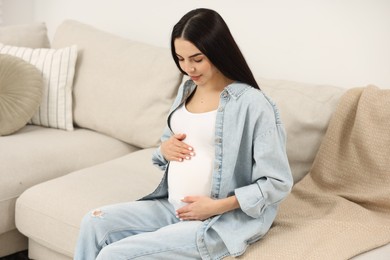 Photo of Pregnant young woman on sofa at home