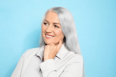 Smiling woman with ash hair color on light blue background