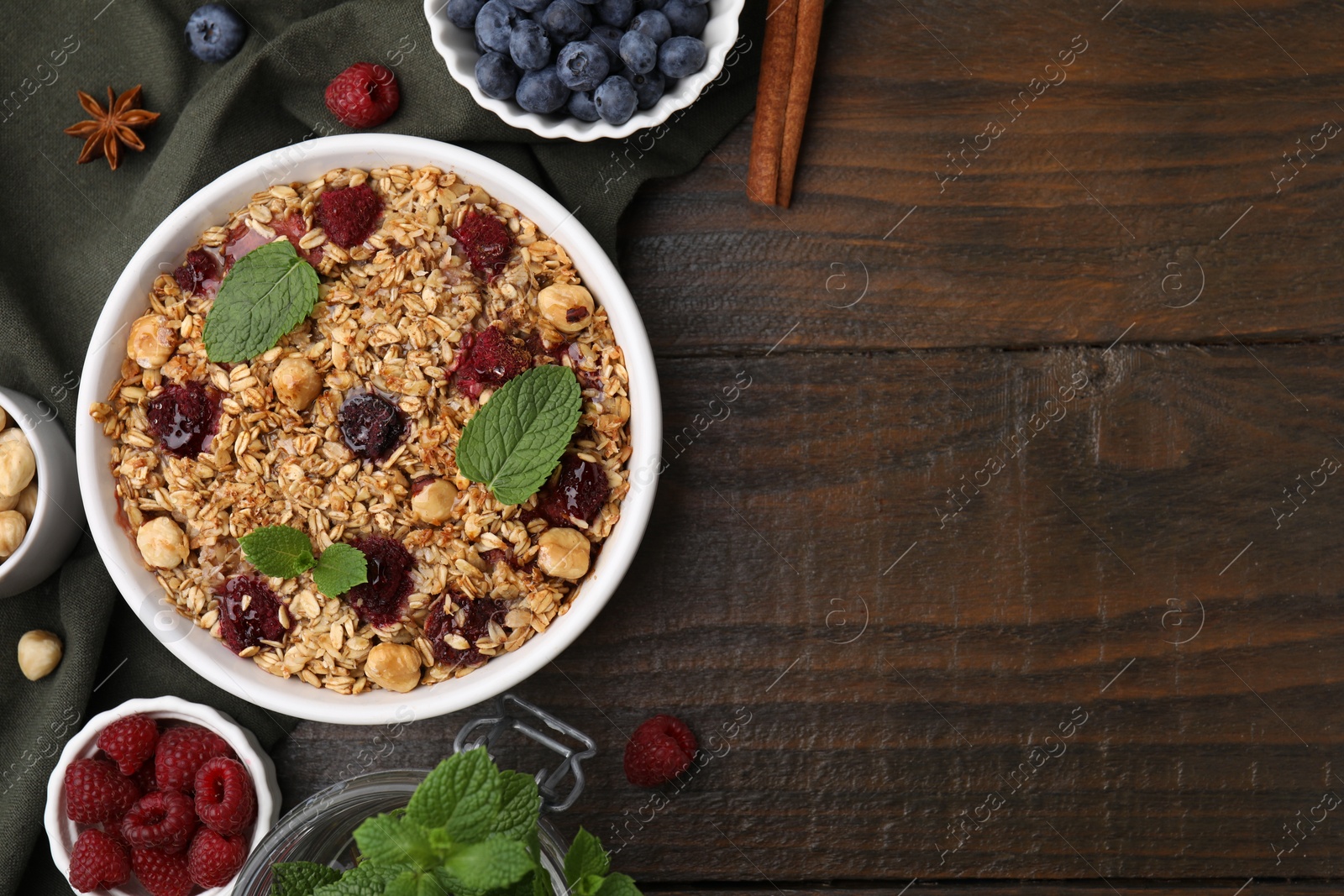Photo of Tasty baked oatmeal with berries and nuts on wooden table, flat lay. Space for text