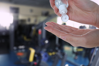 Woman applying antiseptic gel at gym, closeup view with space for text. Preventive measures during epidemic period 