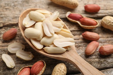 Photo of Fresh peanuts and spoon on wooden table, closeup