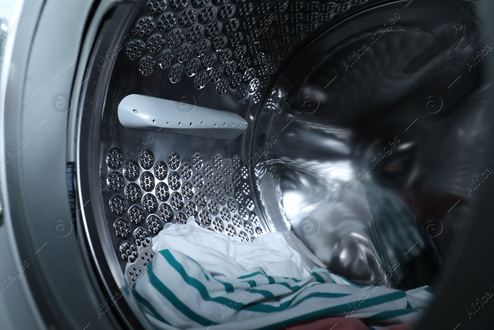 Photo of Modern washing machine drum with laundry, closeup