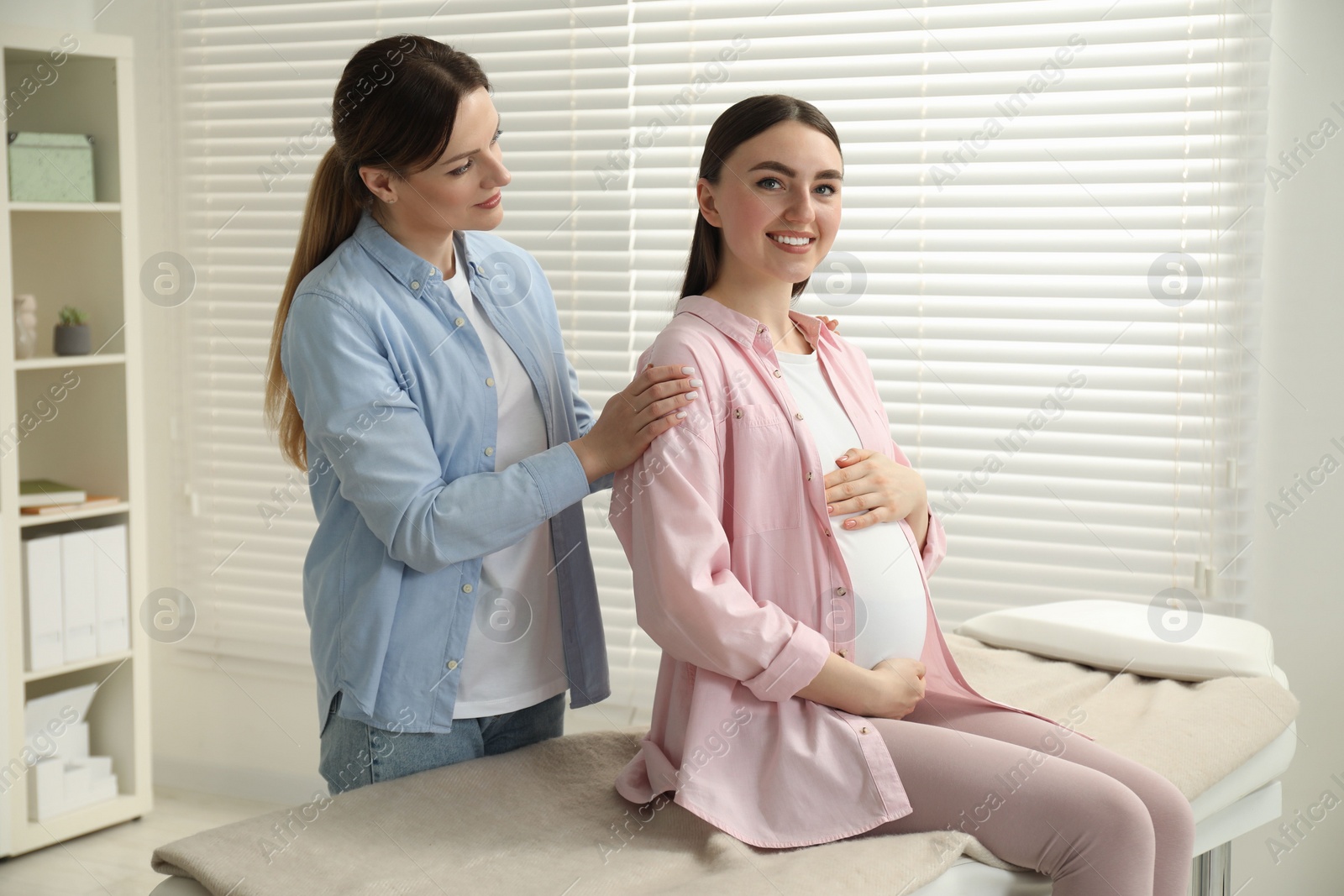 Photo of Doula taking care of pregnant woman indoors. Preparation for child birth