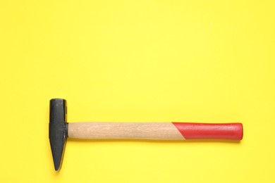 New hammer with wooden handle on yellow background, top view. Space for text