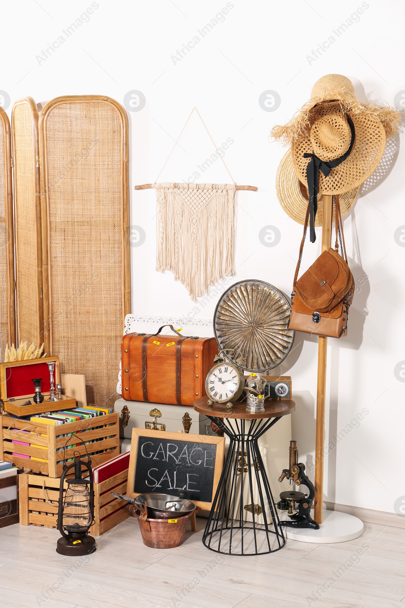 Photo of Sign Garage Sale written on blackboard near many different stuff indoors