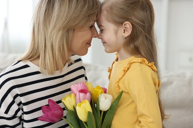 Little daughter congratulating her mom with bouquet of beautiful tulips at home. Happy Mother's Day