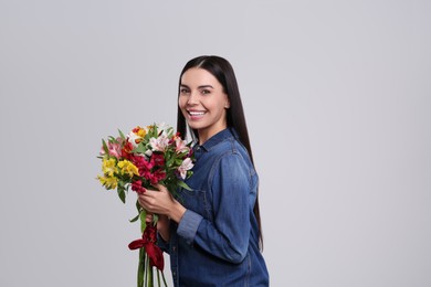 Photo of Happy young woman with beautiful bouquet on light grey background